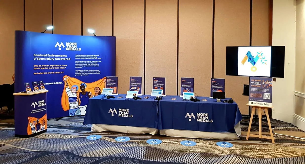 An image of a stand and tables set up with branded illustrations from More Than Medals.